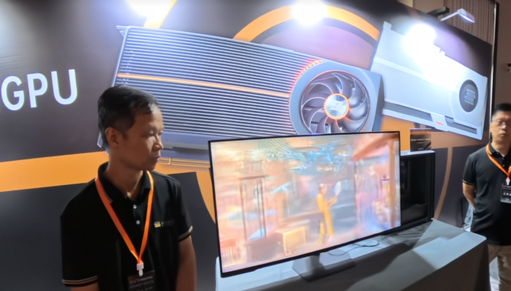 Expo booth with GPU display, screen showing graphics, and two attendees with lanyards.