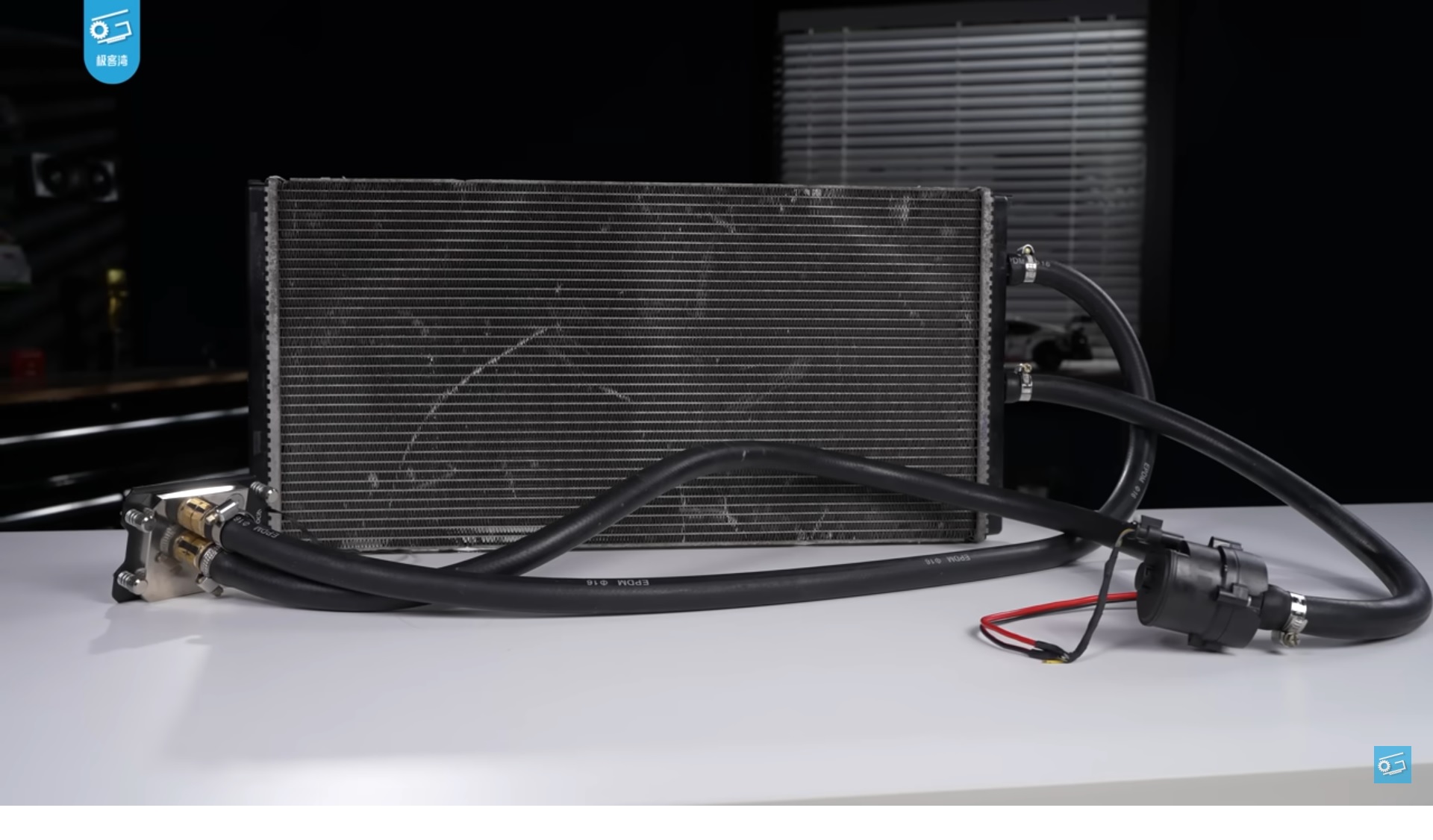 Computer liquid cooling radiator with hoses and pump on white table.