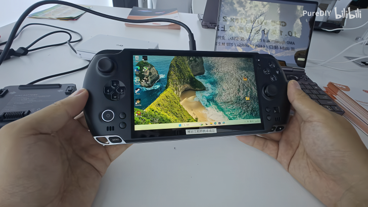 Handheld gaming PC with a Windows desktop screen, showcased on a table.