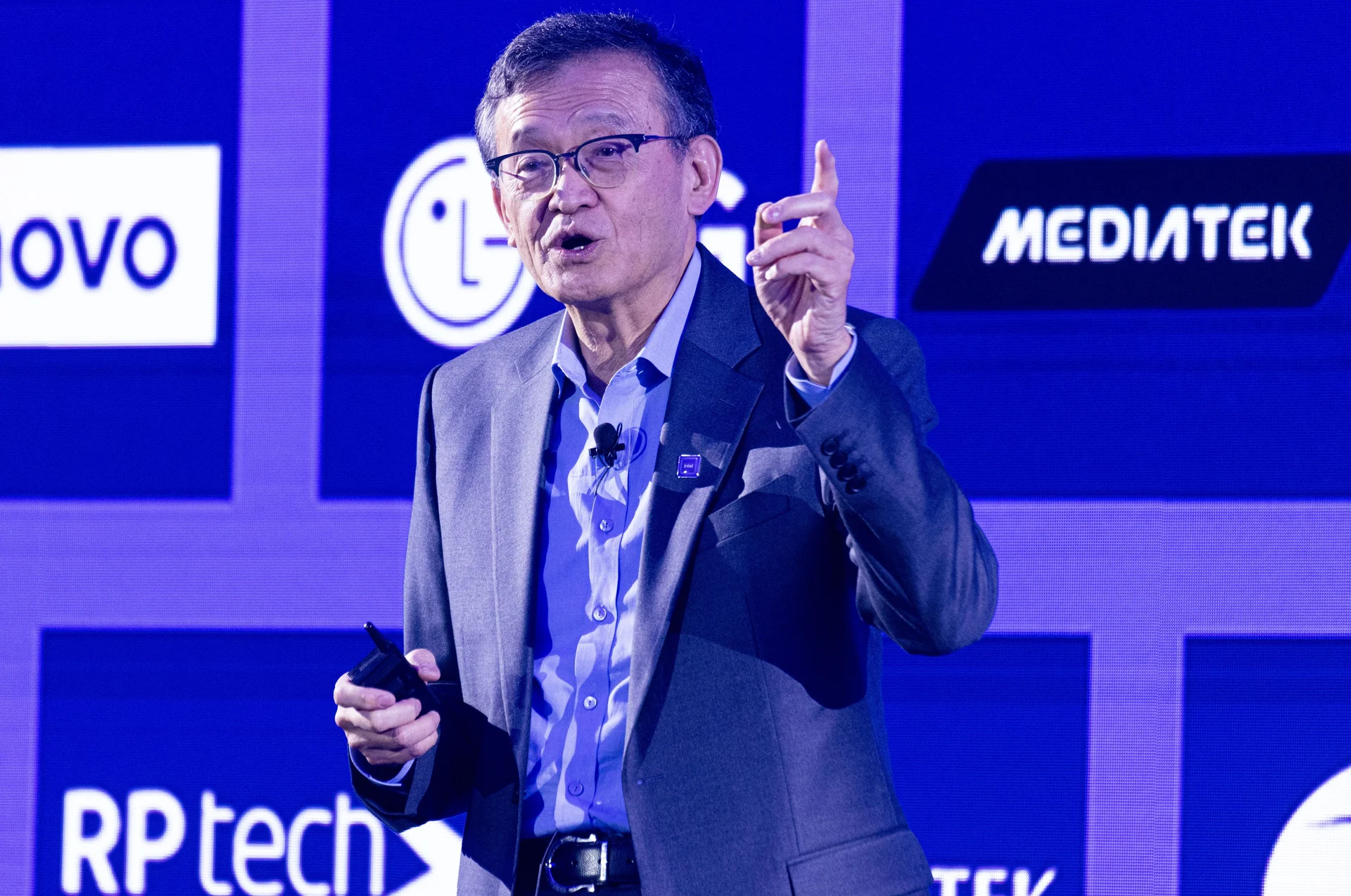 Man speaking at a tech conference with logos in the background.