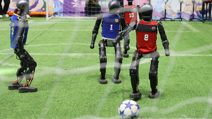 Robots playing soccer on a green field, showcasing advanced technology in sports.
