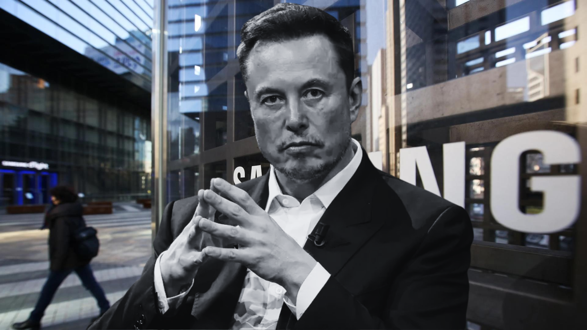 Man in a suit in front of a building with partial SANG visible on glass.