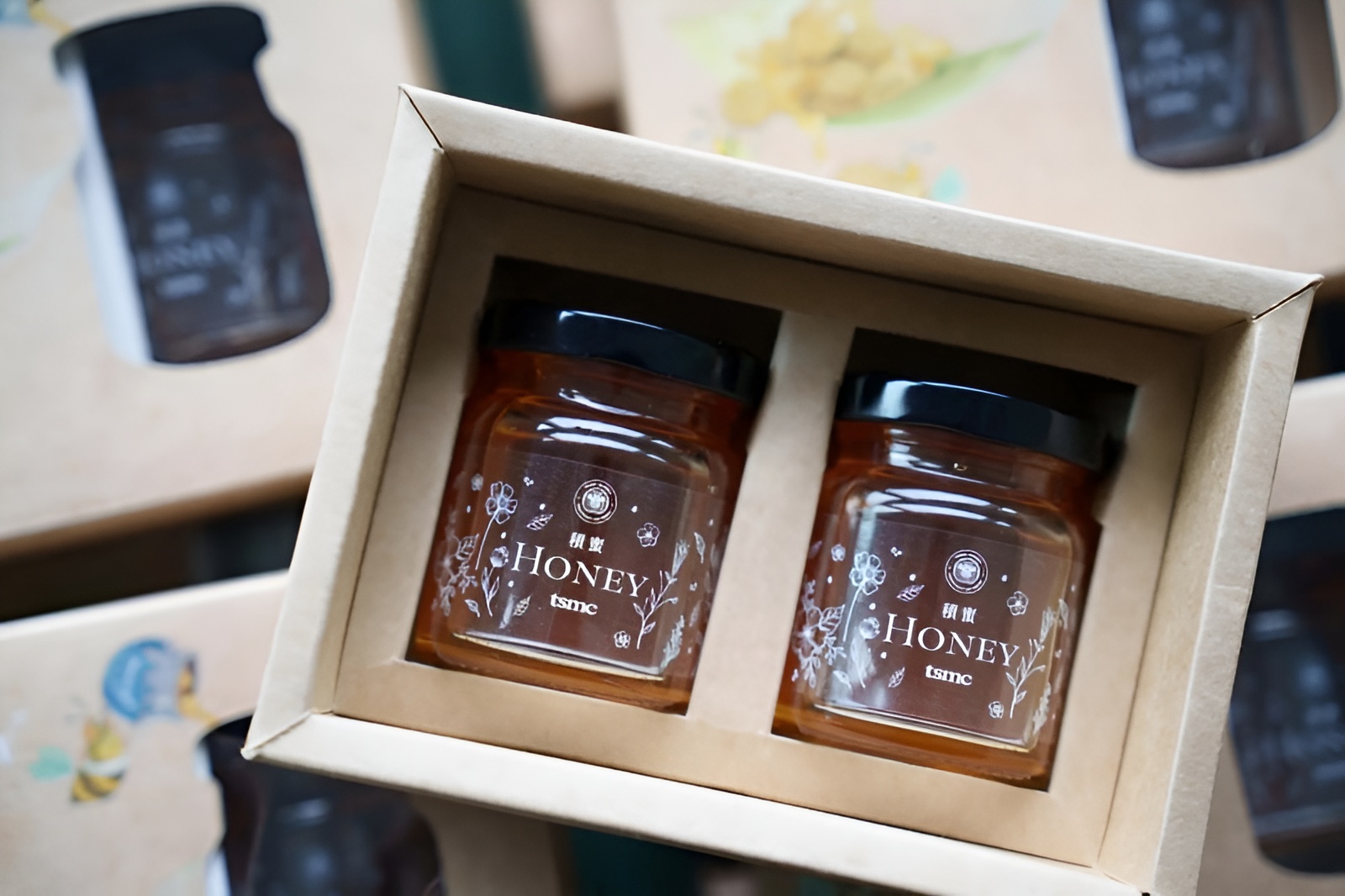 Two jars of Honey tsmc in a cardboard box with floral graphics.