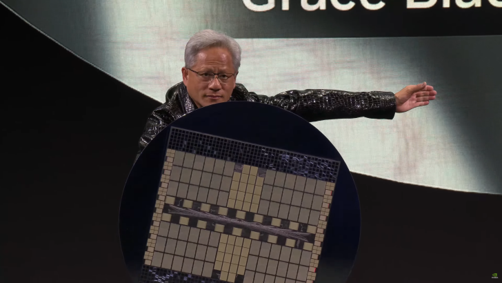 Person on stage holding a large NVIDIA chip with the text Grace on the screen behind.