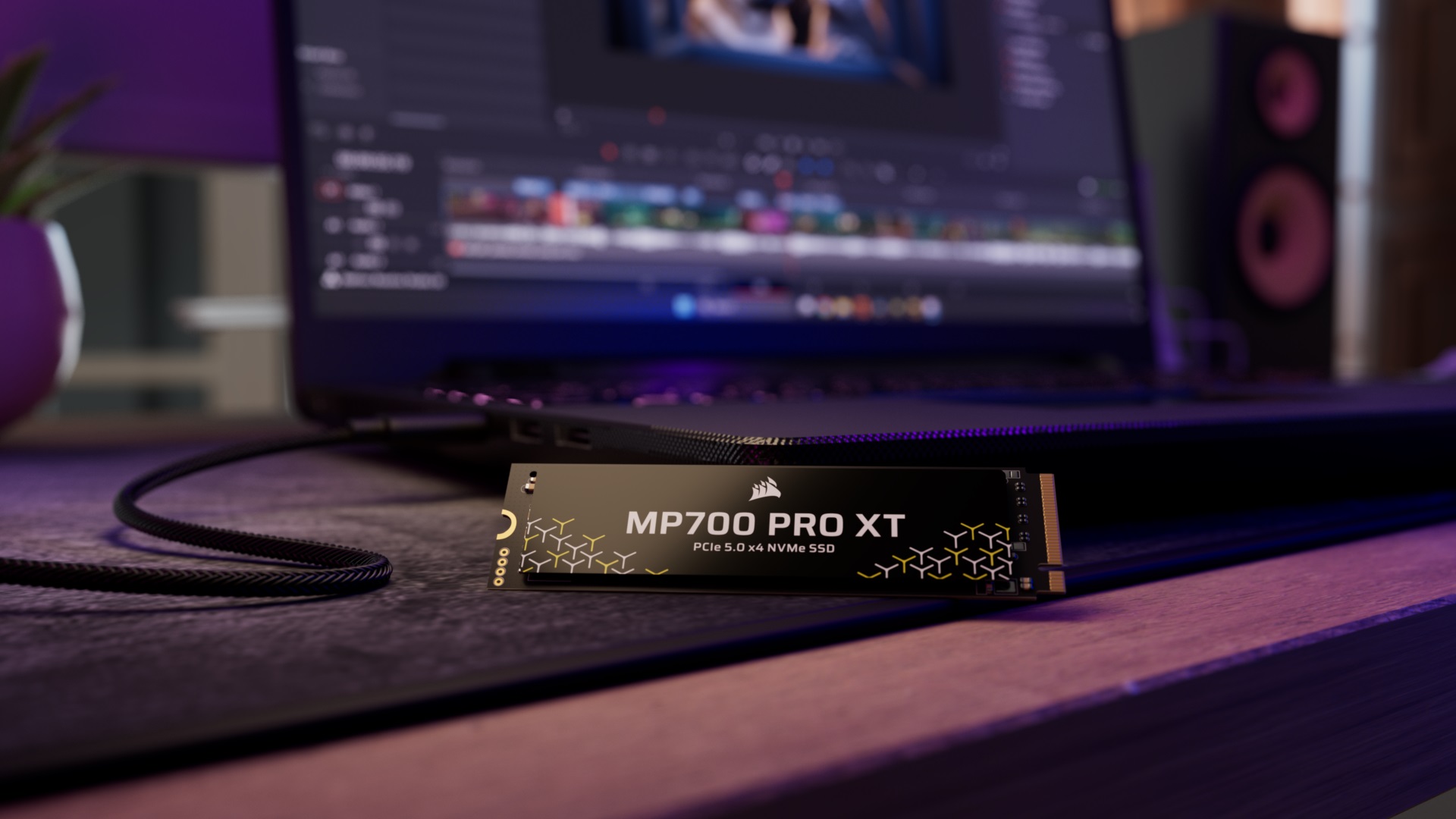 Corsair MP700 PRO XT PCIe 5.0 x4 NVMe SSD on a desk next to a laptop.