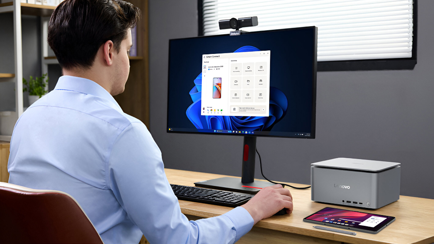 Man using Windows 11 on a Lenovo computer with a webcam, alongside a Lenovo device on the desk.