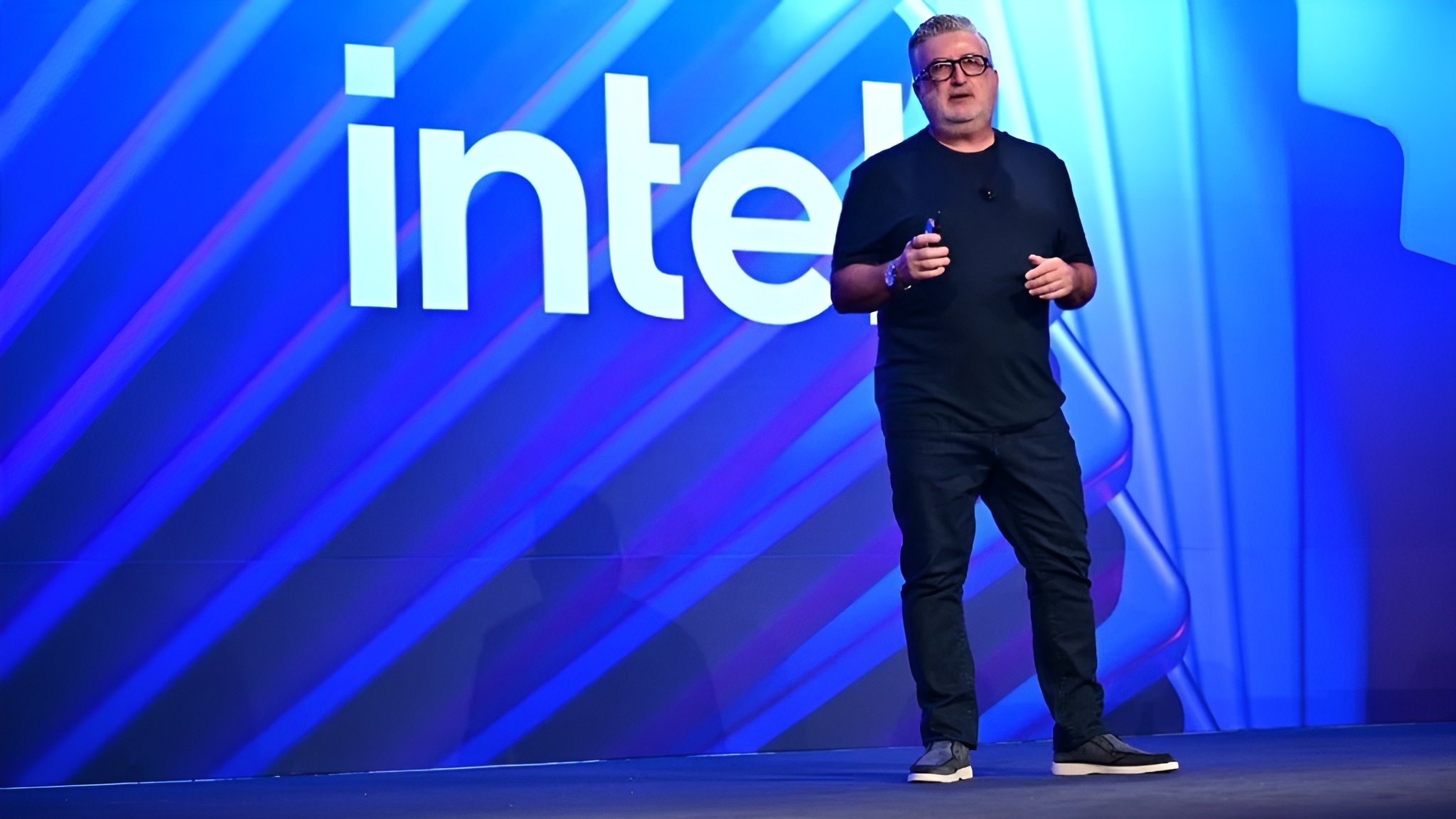Man speaking on stage with prominent intel logo in the background.