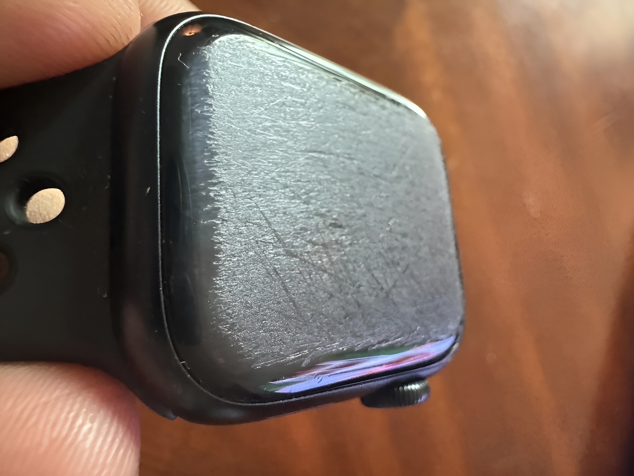 A close-up of a heavily scratched screen on an unbranded black smartwatch.