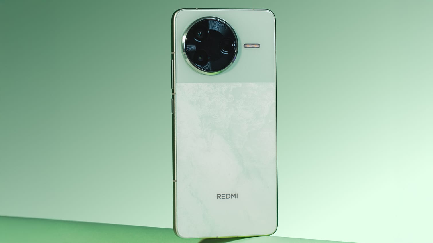 A Redmi smartphone with a large circular camera module and 'REDMI' branding on the marbled back, set against a green gradient background.