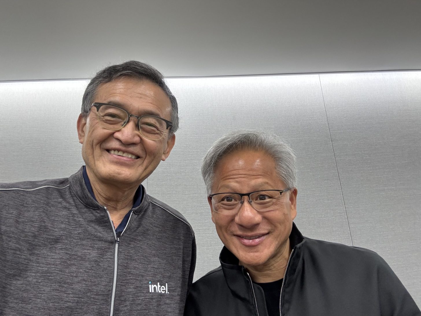 Two smiling men, one wearing an 'intel' branded jacket, posing together indoors.