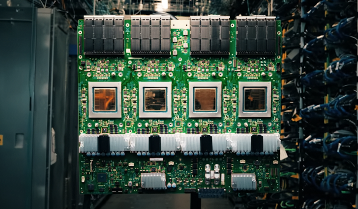 A large, green circuit board with four prominent chips is mounted vertically within a data center environment.
