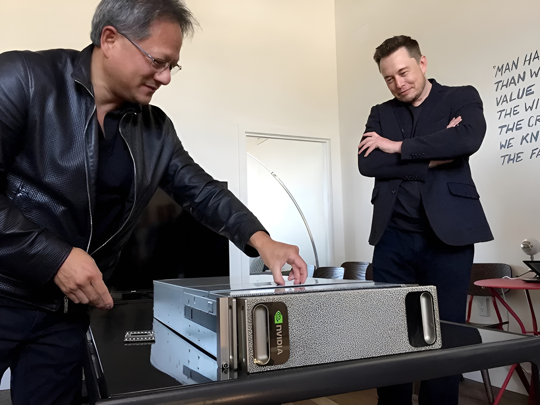 Two individuals examining an NVIDIA-branded server unit in an office setting with a motivational quote on the wall.