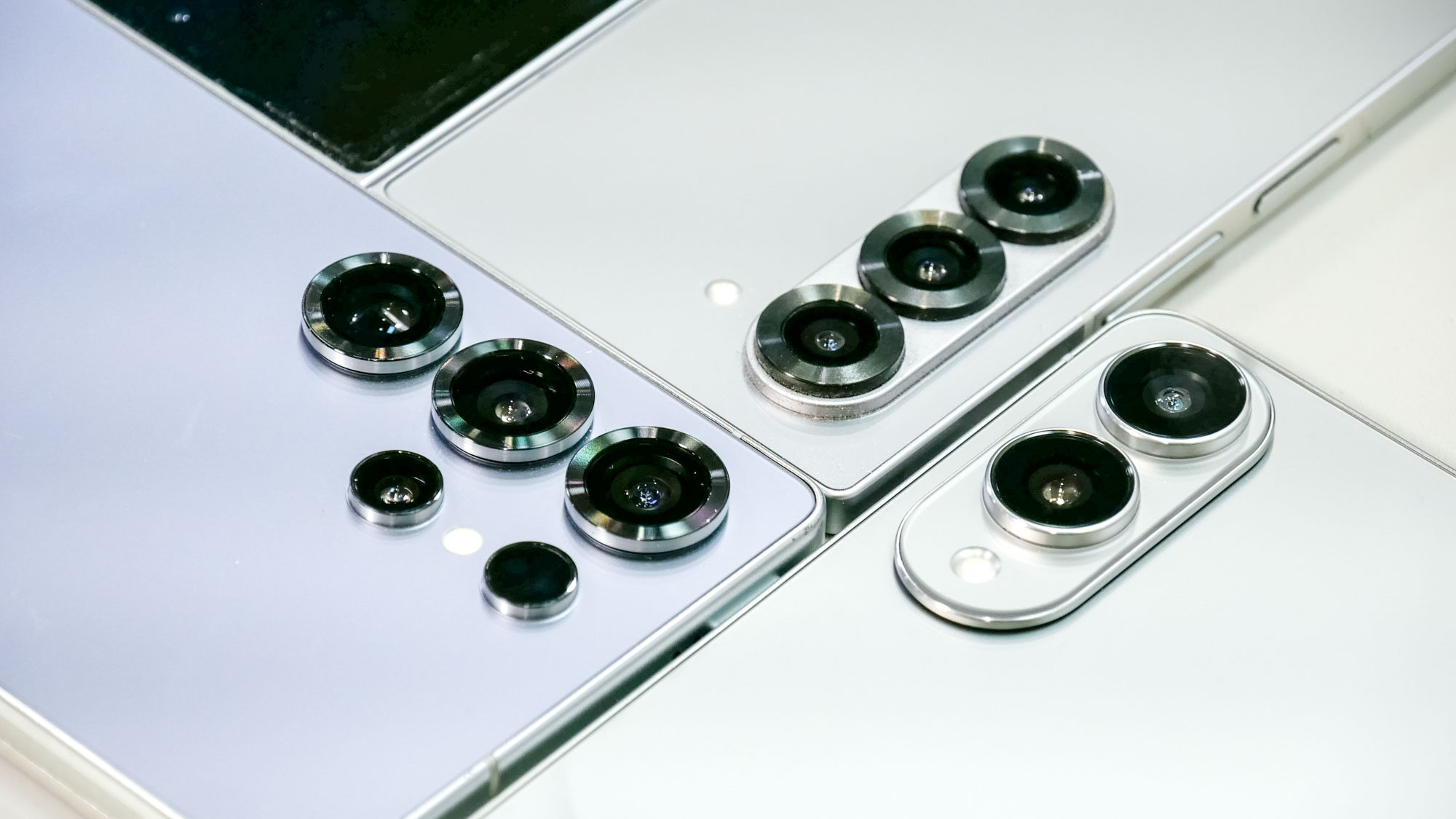 Close-up of three smartphones with multiple rear camera lenses, showcasing distinct camera module designs and metallic finishes.