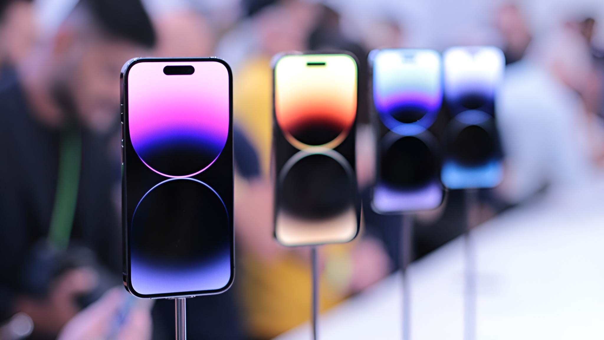 A lineup of Apple iPhone 14 Pro smartphones displayed on stands, featuring their bright, colorful screens with the Dynamic