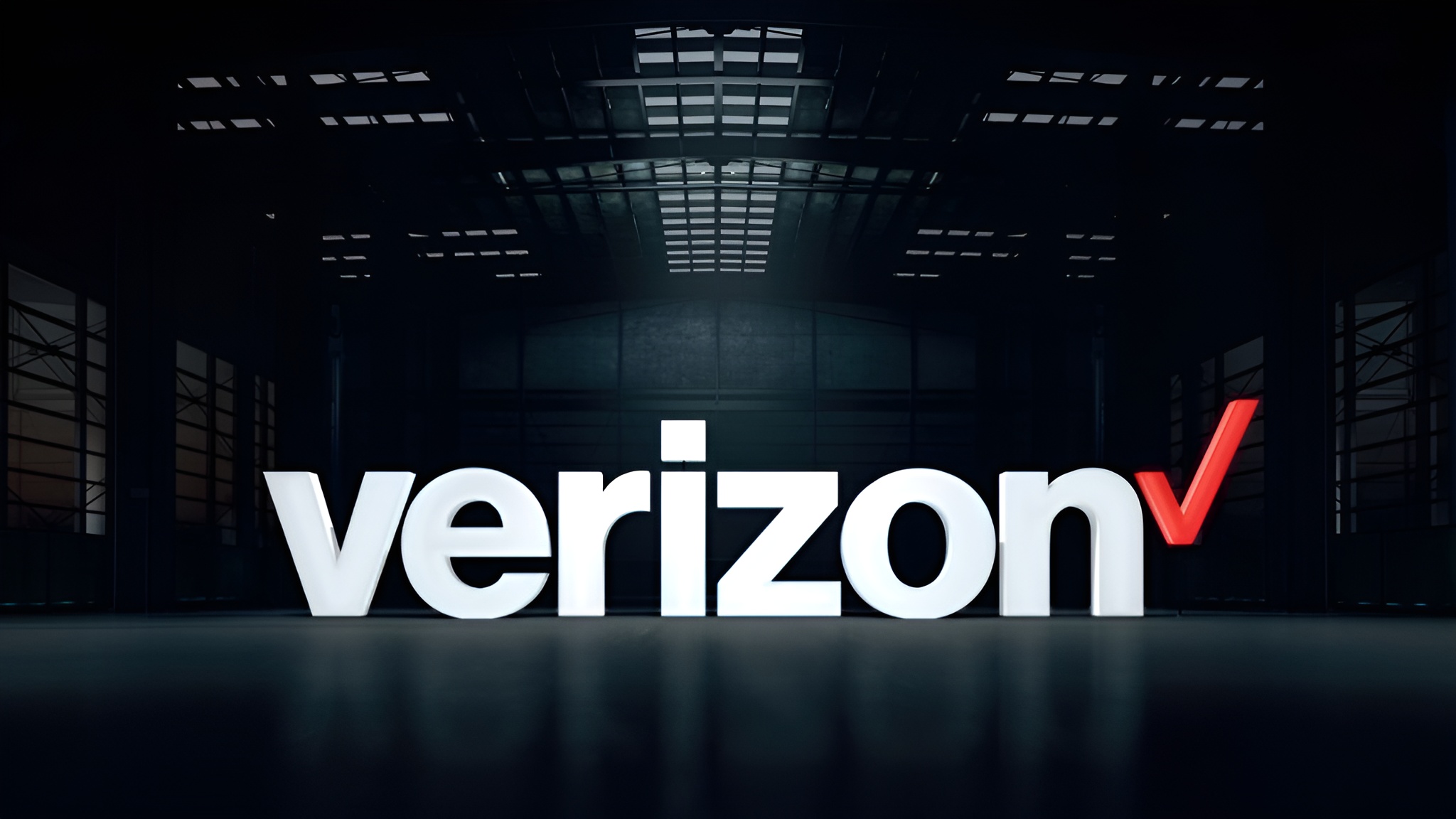 The Verizon logo is prominently displayed in large, illuminated letters inside a dimly lit industrial-style building.