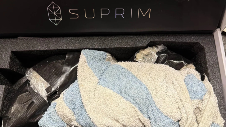 A box labeled 'SUPRIM' contains a packaged item covered with a striped towel.