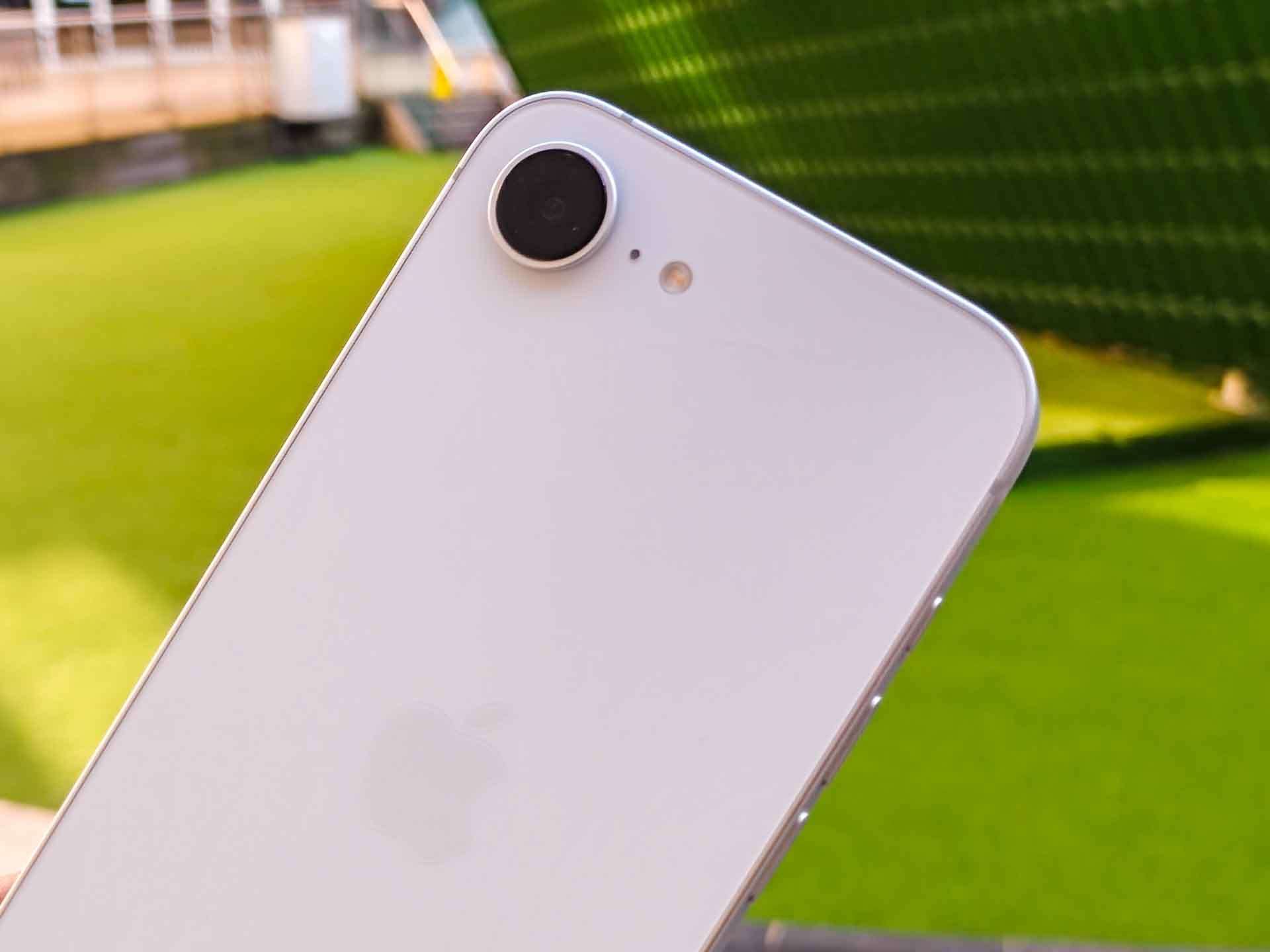 A close-up of an Apple iPhone SE's rear camera in a bright outdoor setting.