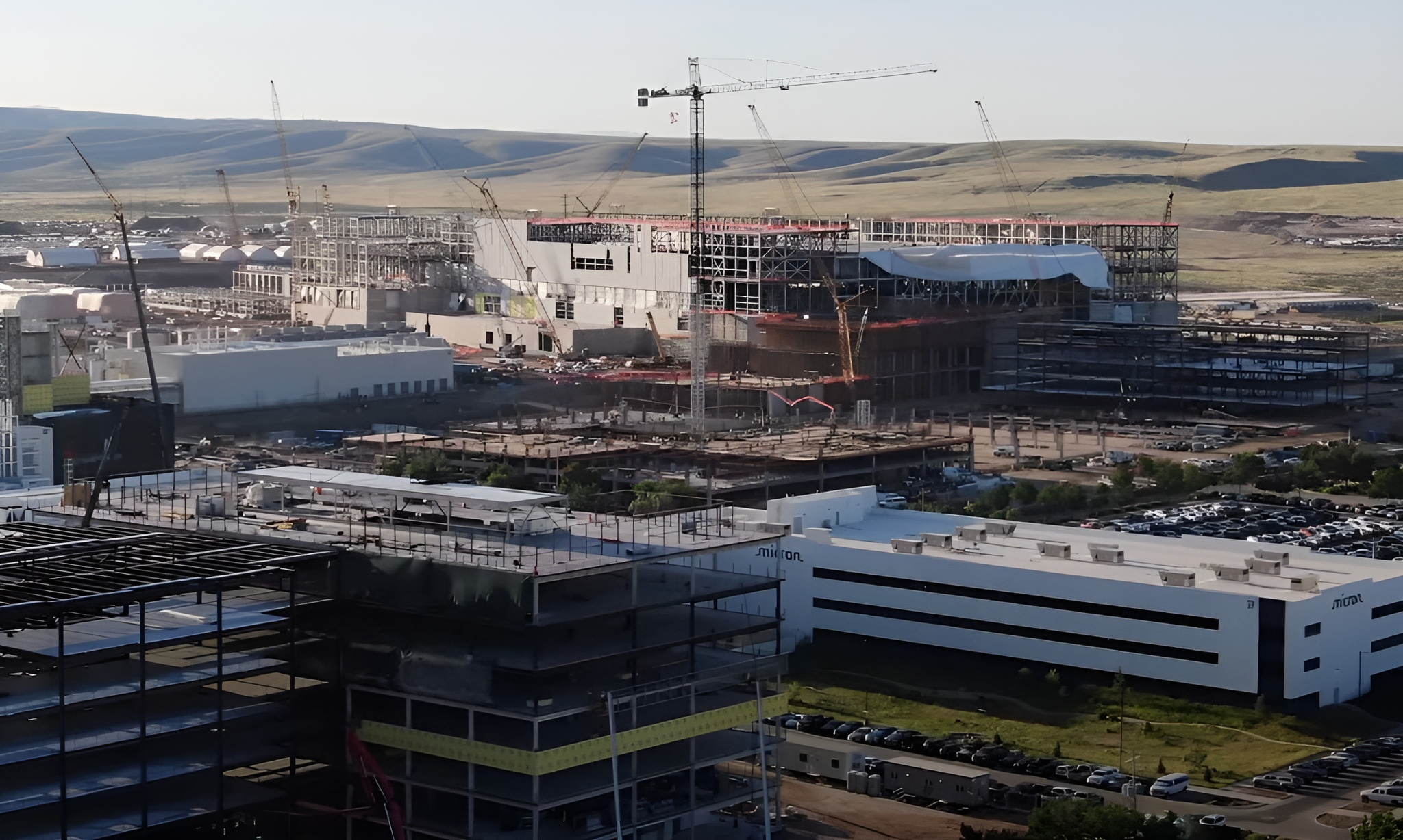 Aerial view of a construction site with multiple cranes, showing a large building under construction near a Micron