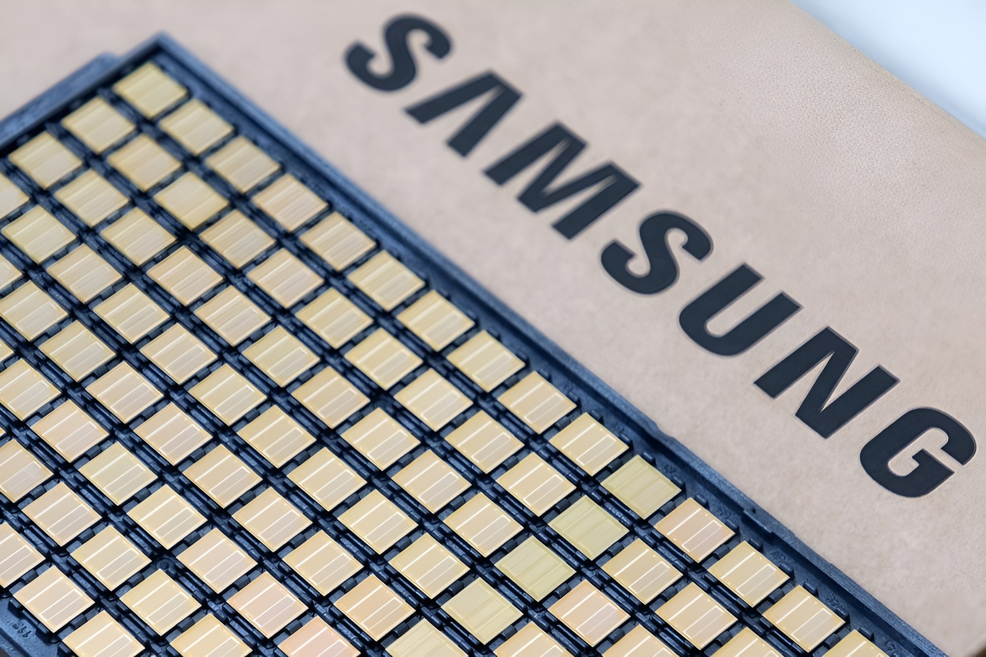 A close-up of a Samsung semiconductor chip featuring a grid of golden connectors.