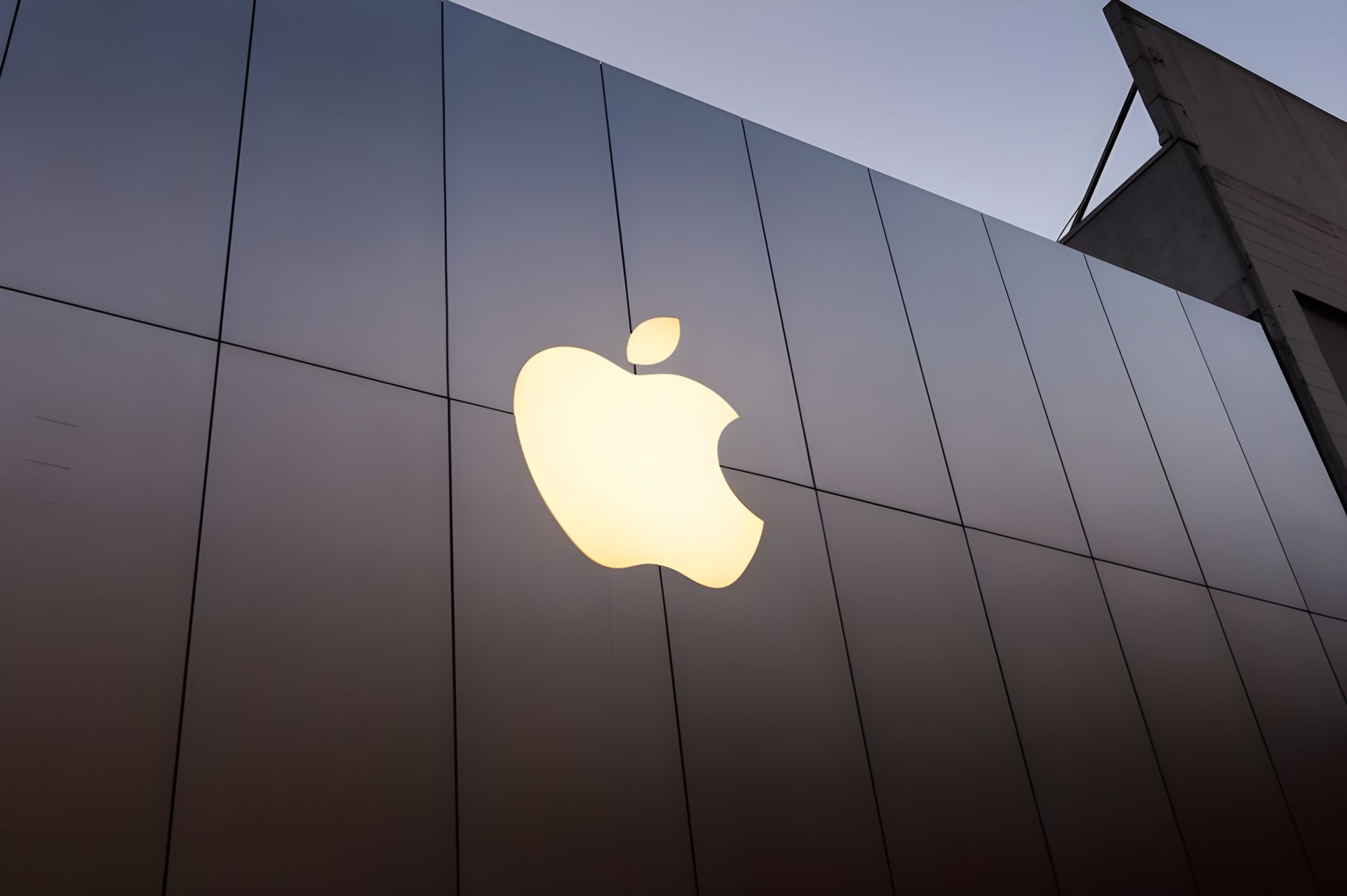 An illuminated Apple logo is displayed on the facade of an Apple Store.