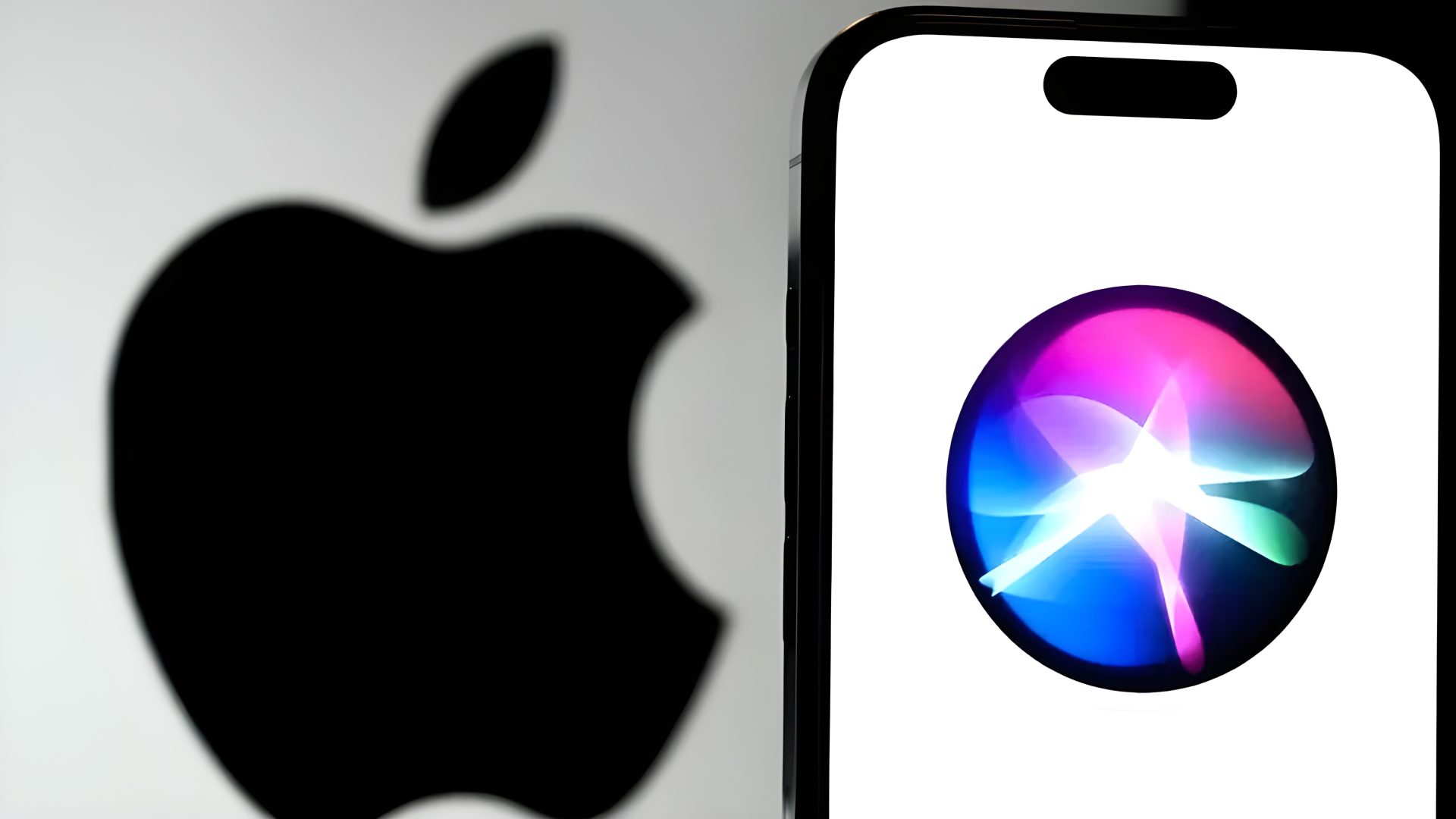 An iPhone displaying the Apple Siri logo on its screen, with a blurred Apple logo in the background.