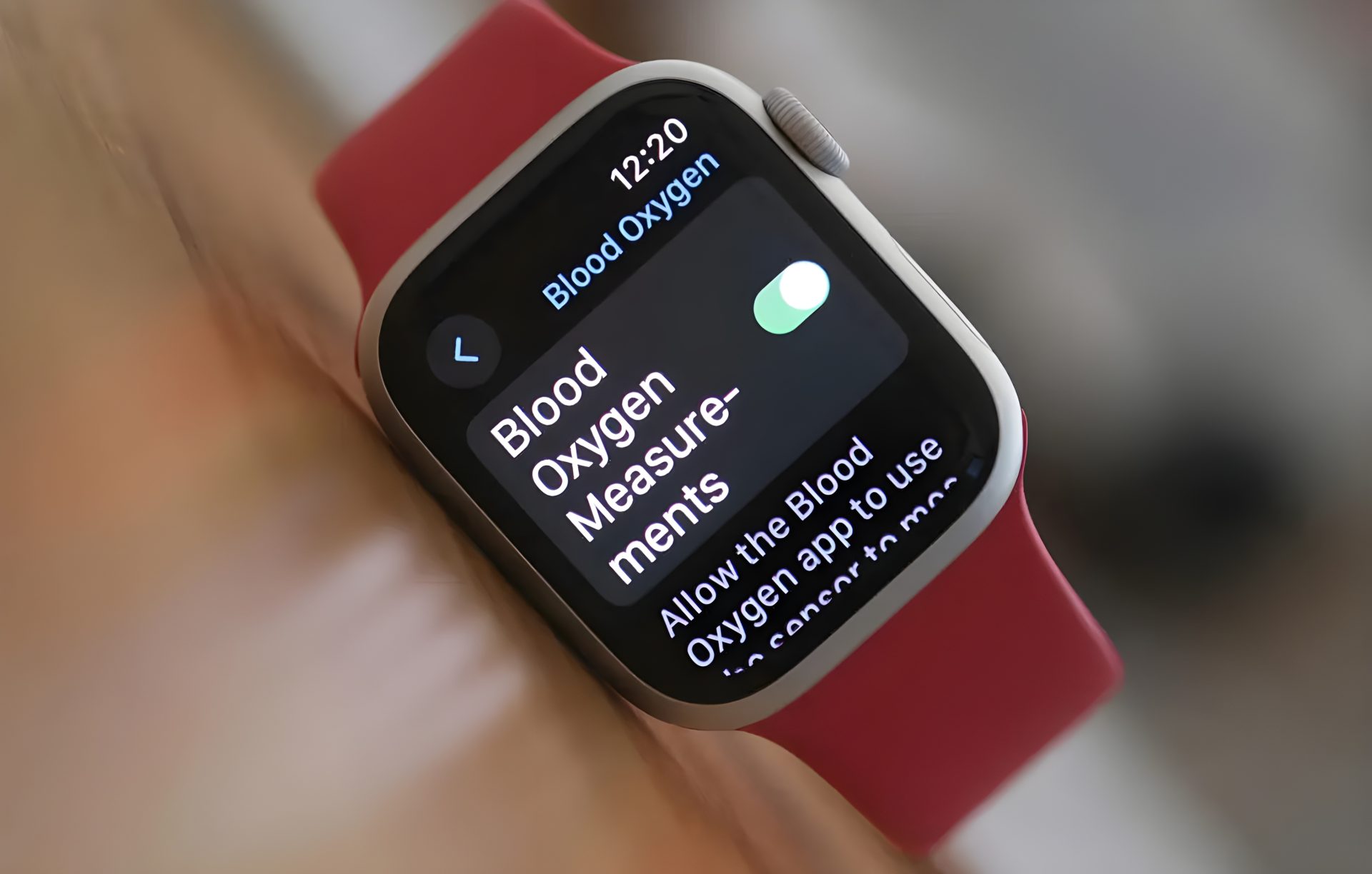 An Apple Watch with a red strap displays the 'Blood Oxygen' measurement screen with the toggle switch turned on.