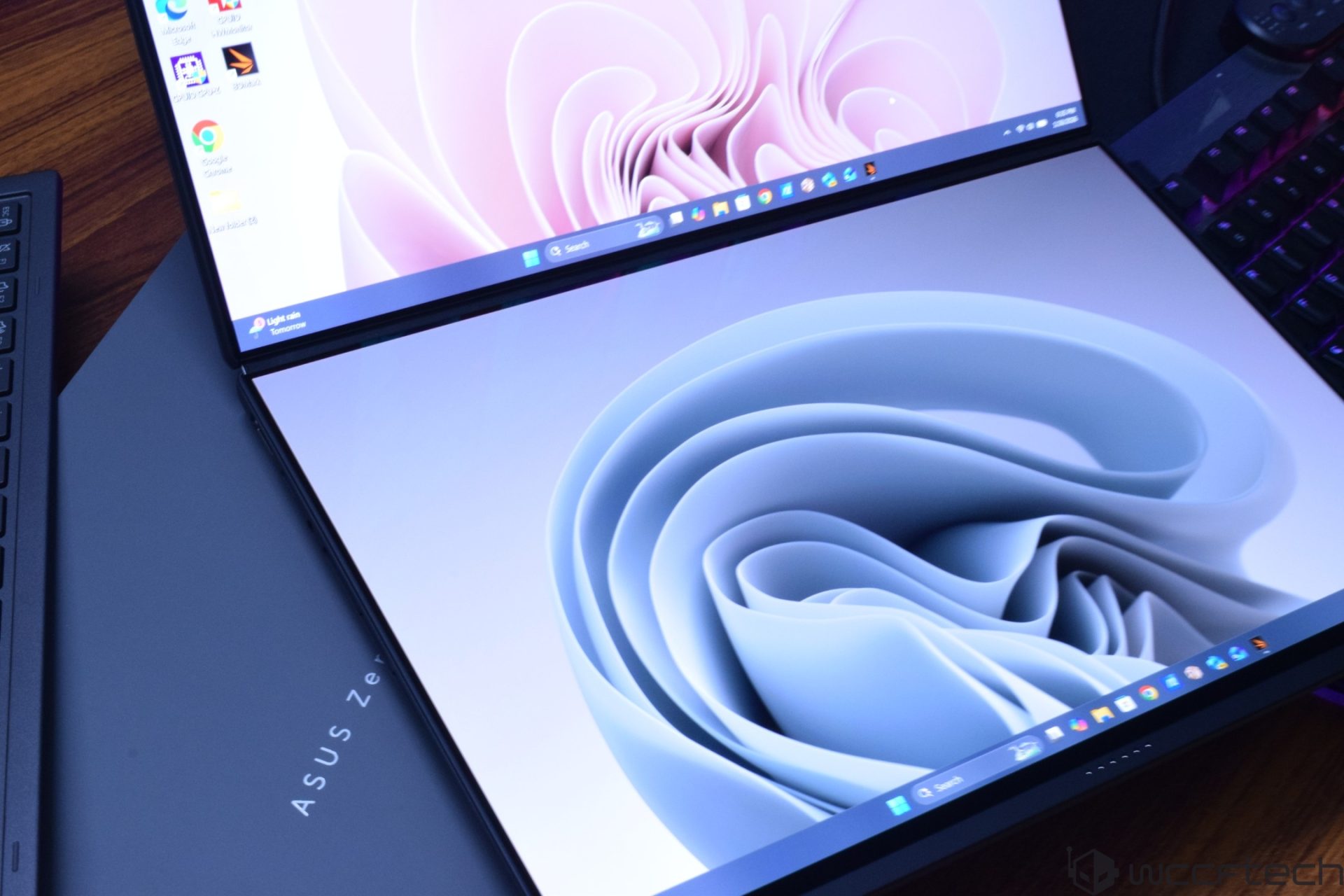 An ASUS Zenbook Fold showing a dual-screen display with abstract wallpapers on both screens.