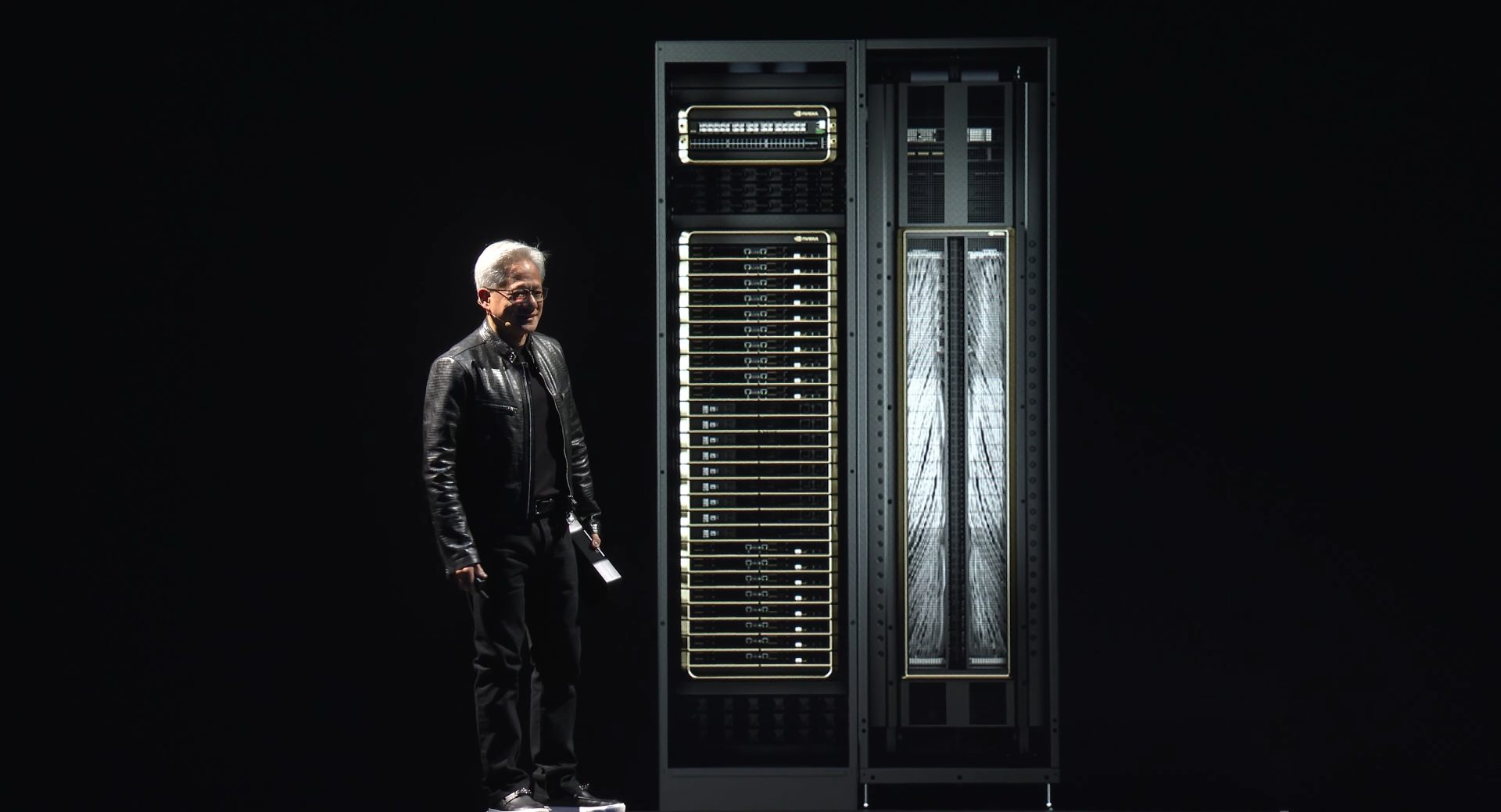 A person stands next to a large NVIDIA data center server rack with multiple GPUs and visible branding.