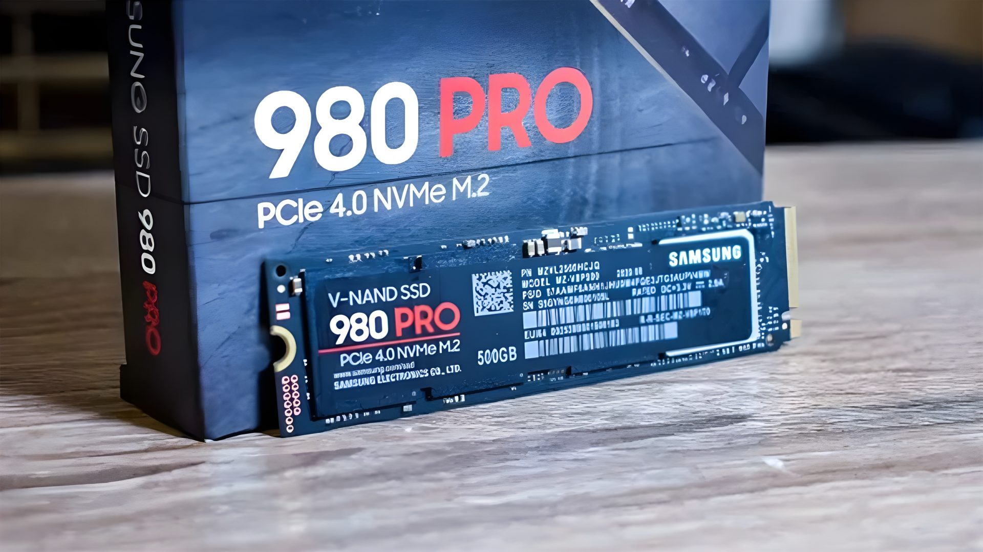 A Samsung 980 PRO PCIe 4.0 NVMe M.2 500GB solid-state drive is placed in front of its packaging box.