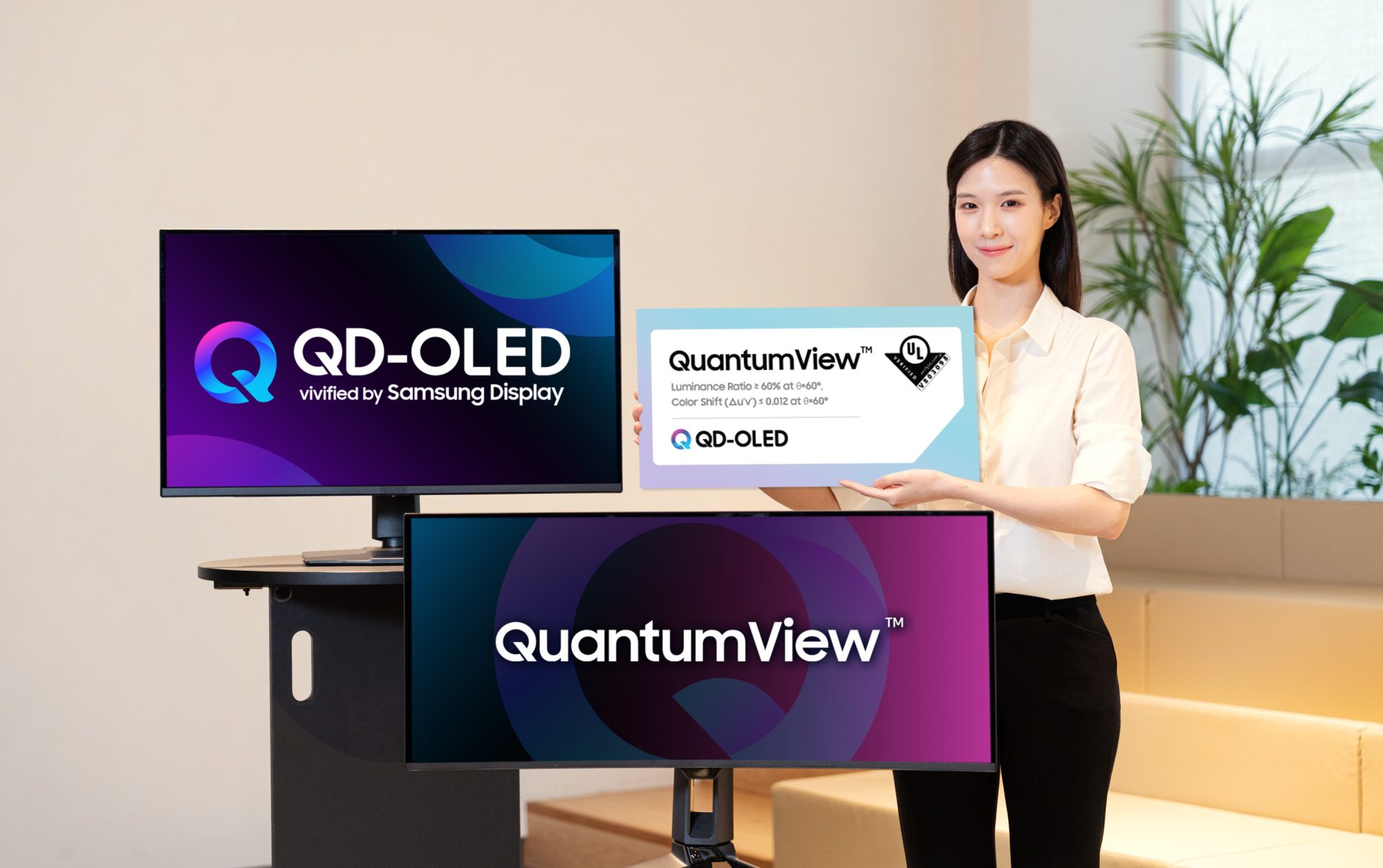 A woman holds a sign displaying 'QuantumView™' next to two monitors showcasing 'QD-OLED vivified by Samsung Display' and 'QuantumView™' logos.