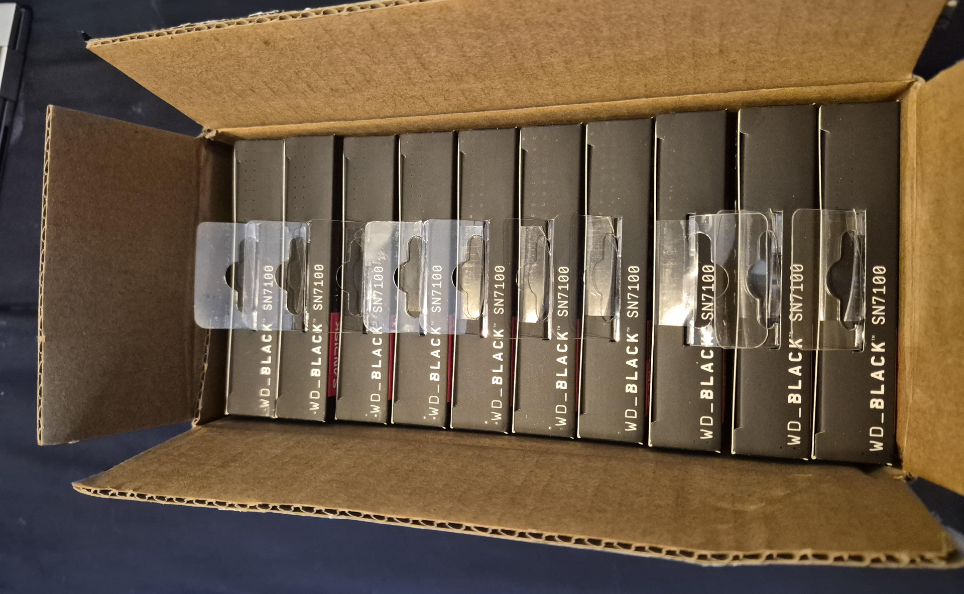A cardboard box contains multiple units of WD_BLACK SN7100 products neatly lined up.