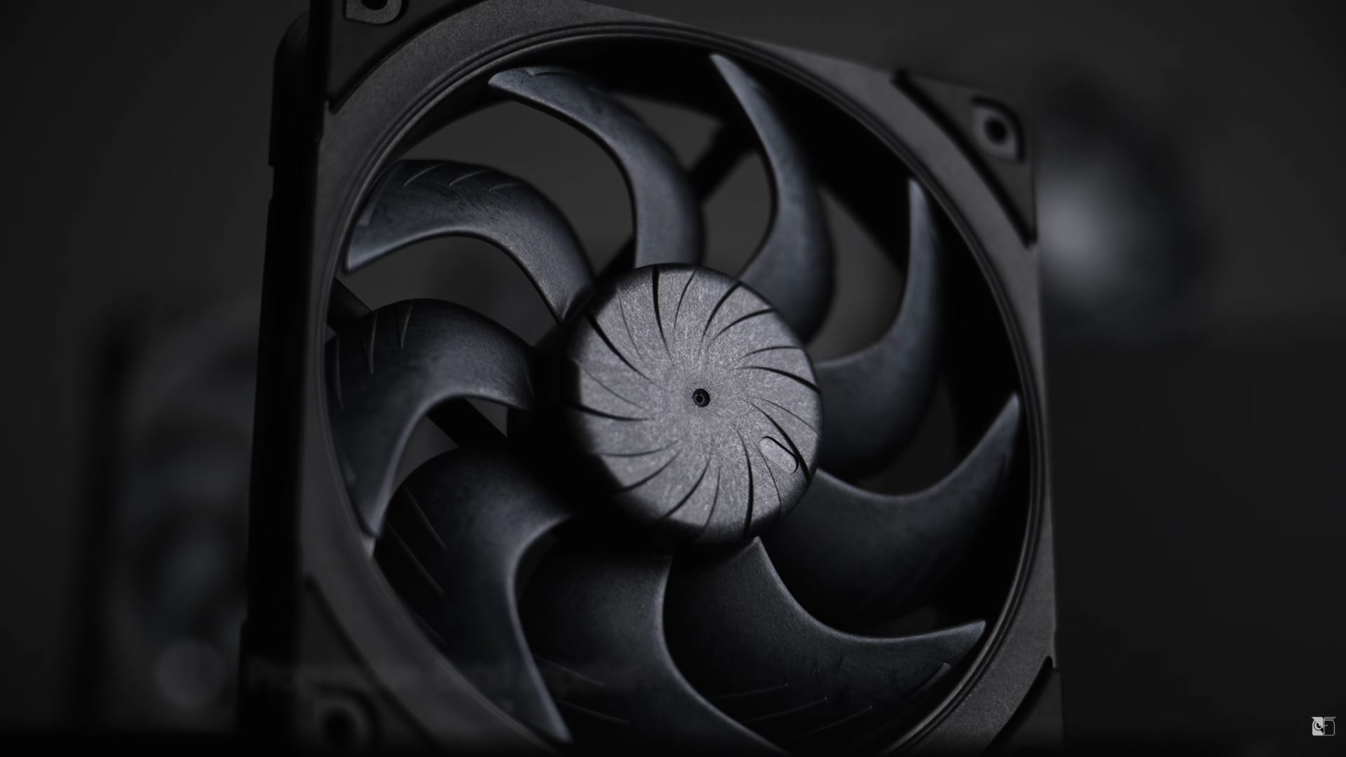 A close-up image of a black, unbranded computer cooling fan with a swirl pattern on its blades.