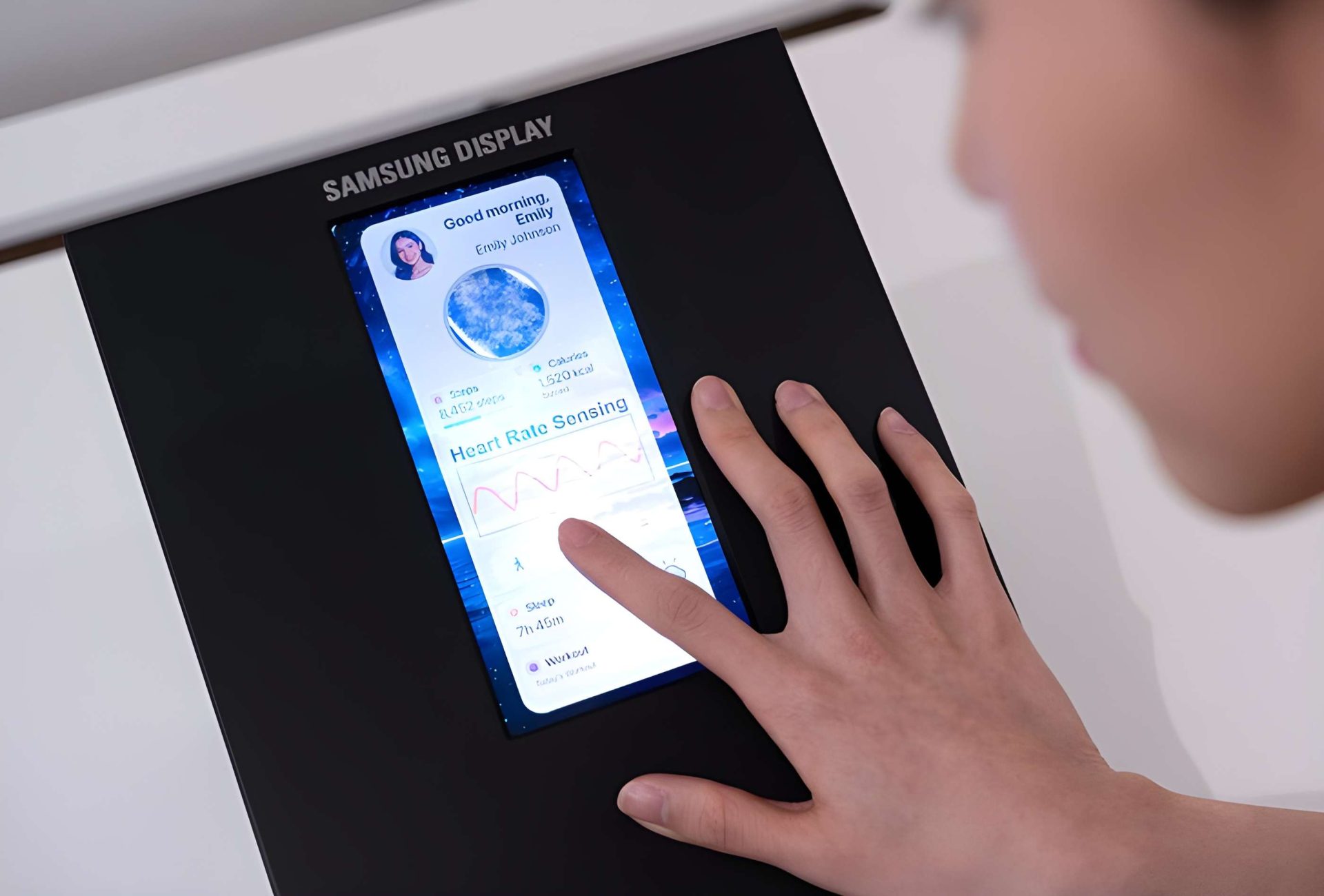 A person interacts with a Samsung Display screen showing health metrics and 'Heart Rate Sensing.'