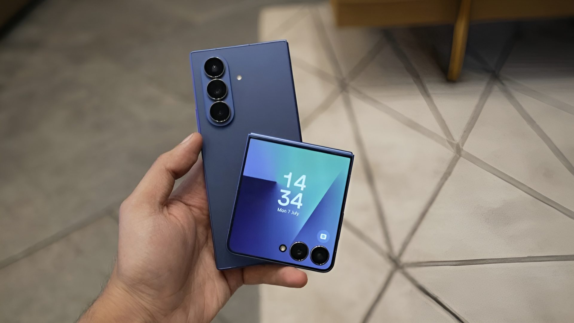 A person holding a Samsung Galaxy Z Fold5 and a Samsung Galaxy Z Flip5, with the latter showing '14:34' and 'Mon 7 July' on