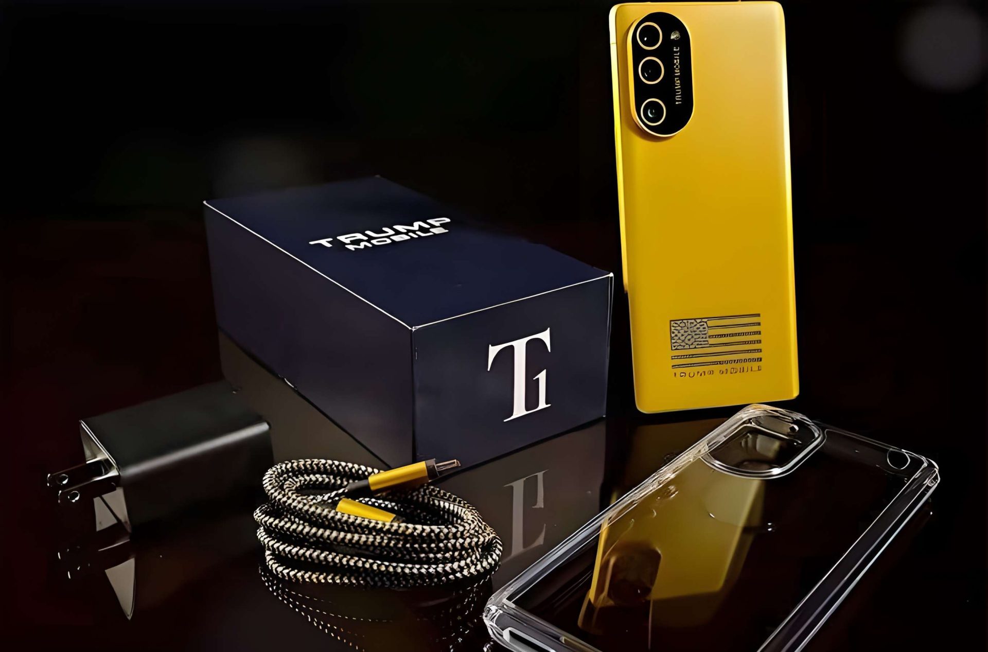 A yellow smartphone labeled 'Trump Mobile' is displayed alongside a charging cable, a plug, a clear phone case, and a branded box with a large 'T' logo.