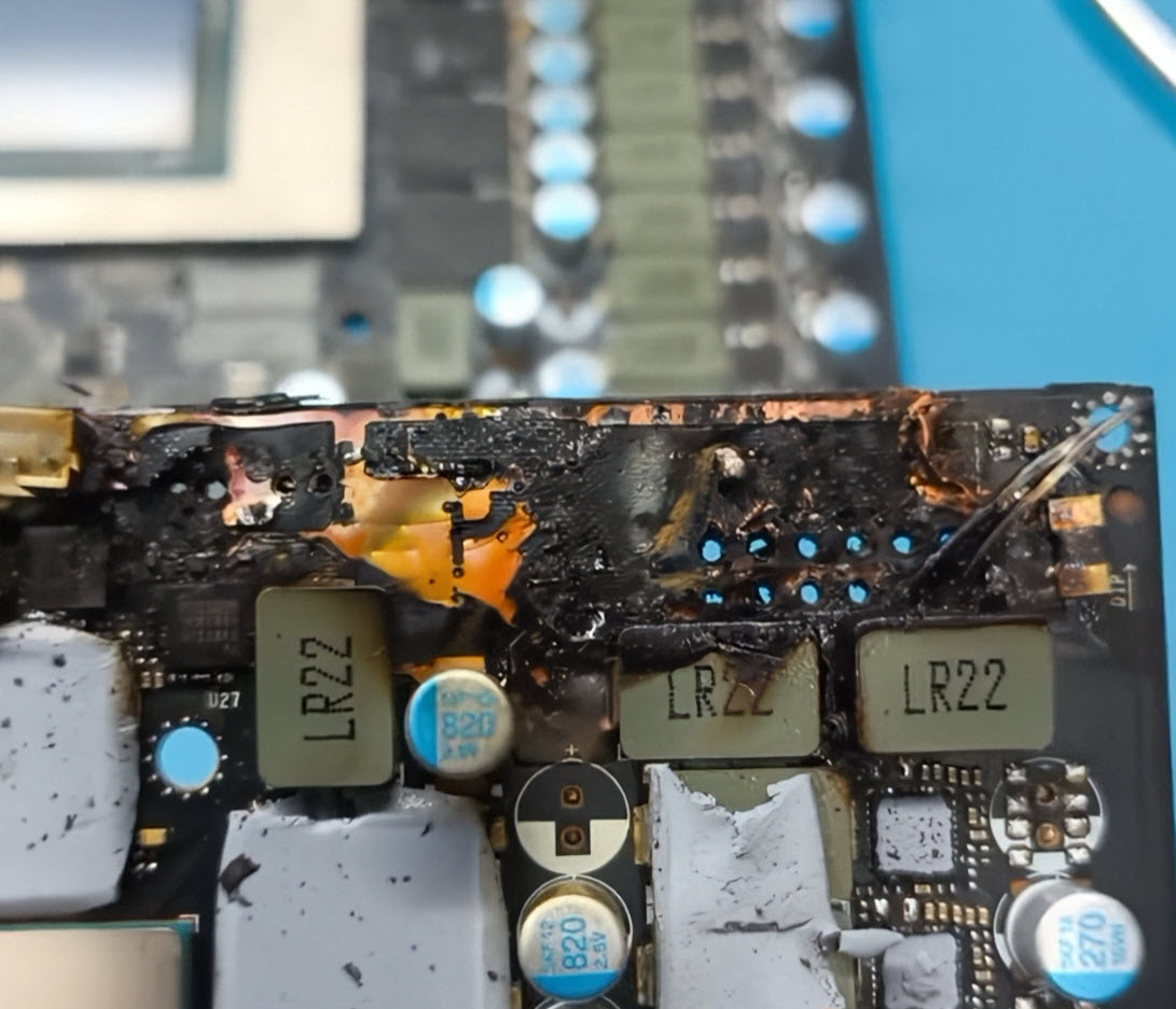 A close-up of a burnt and damaged circuit board with components labeled 'LR22' and capacitors marked '820 2.5V'.