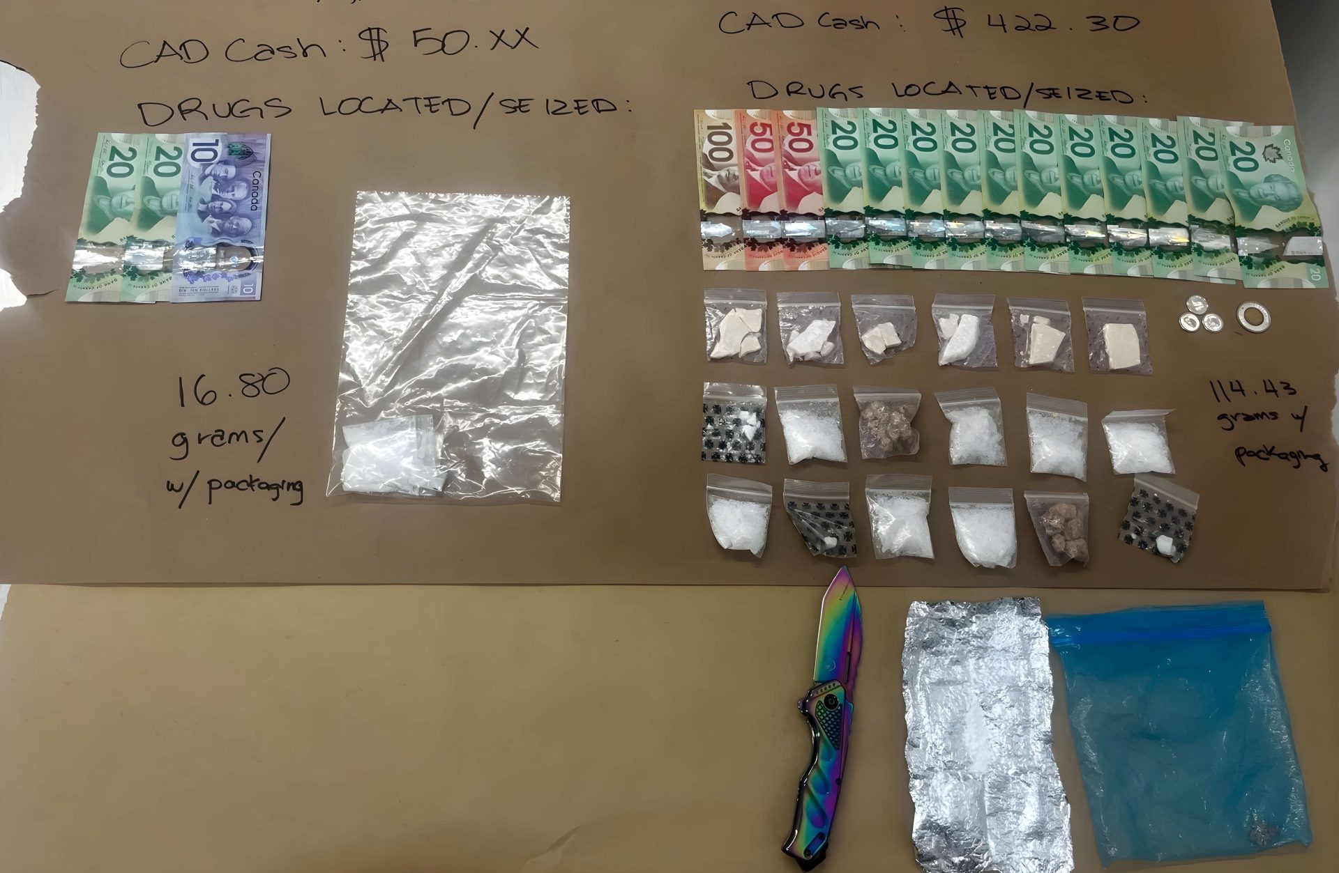 Canadian cash, multiple bags containing various substances, and a multicolored knife arranged on a table with handwritten notes of cash totals and drug weights.