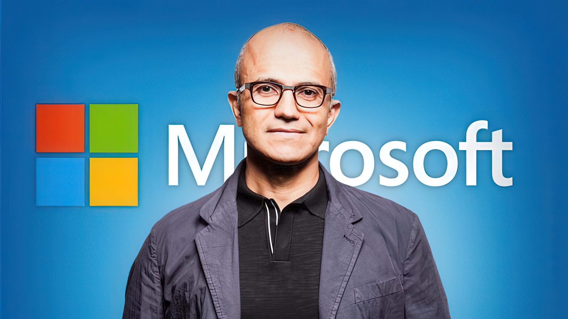 Satya Nadella in front of a large Microsoft logo on a blue background talking about AI.