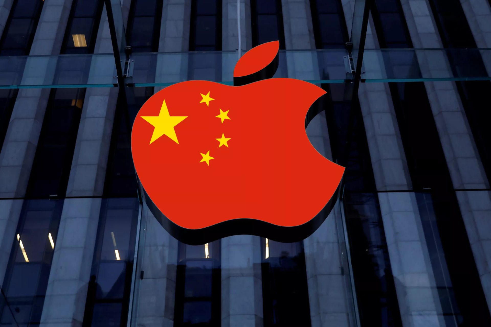 The Apple logo with a design of the Chinese flag is superimposed over a building's glass facade.
