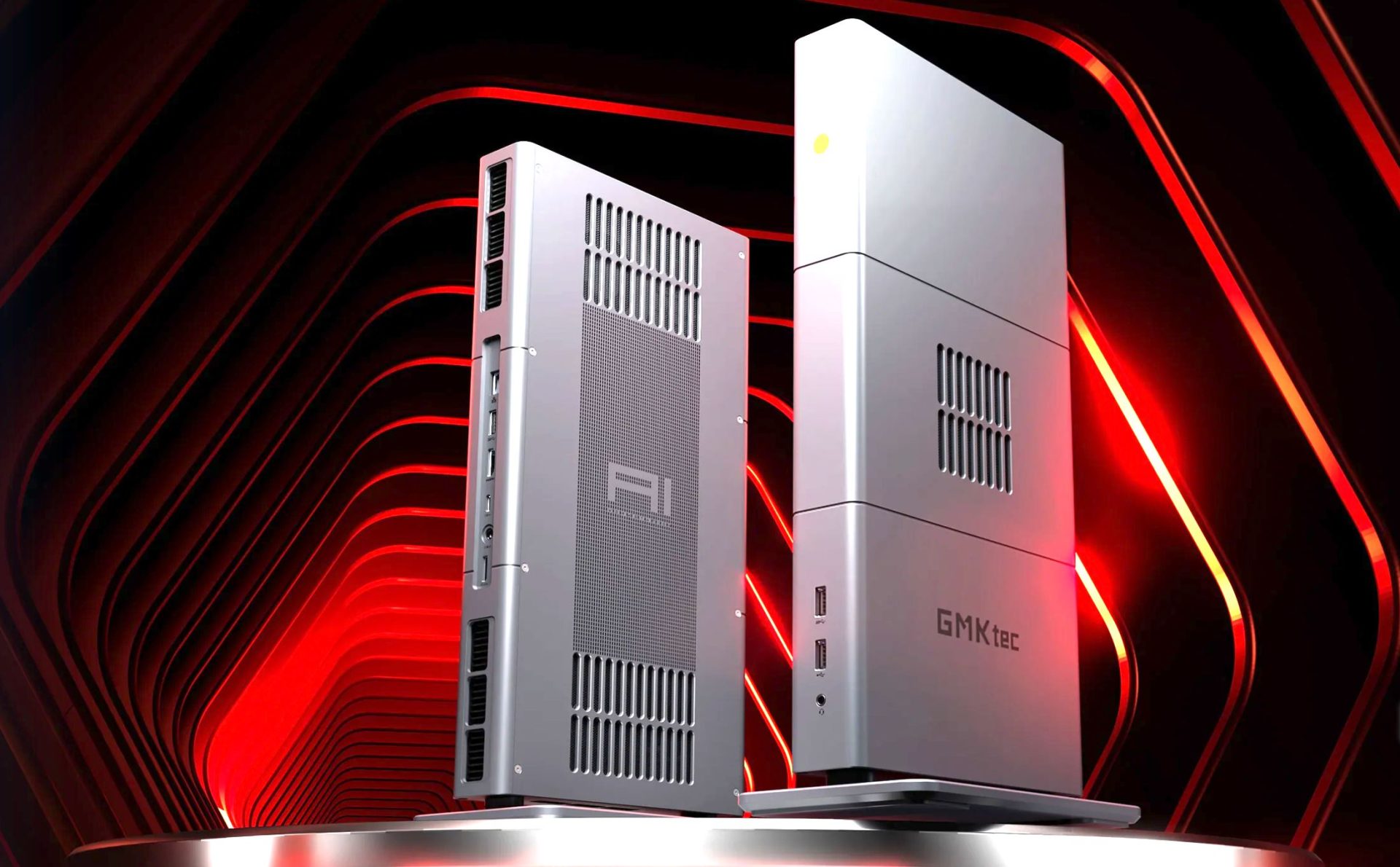 Two modern slim desktop PCs labeled AI and GMKtec are showcased against a red geometric backdrop.