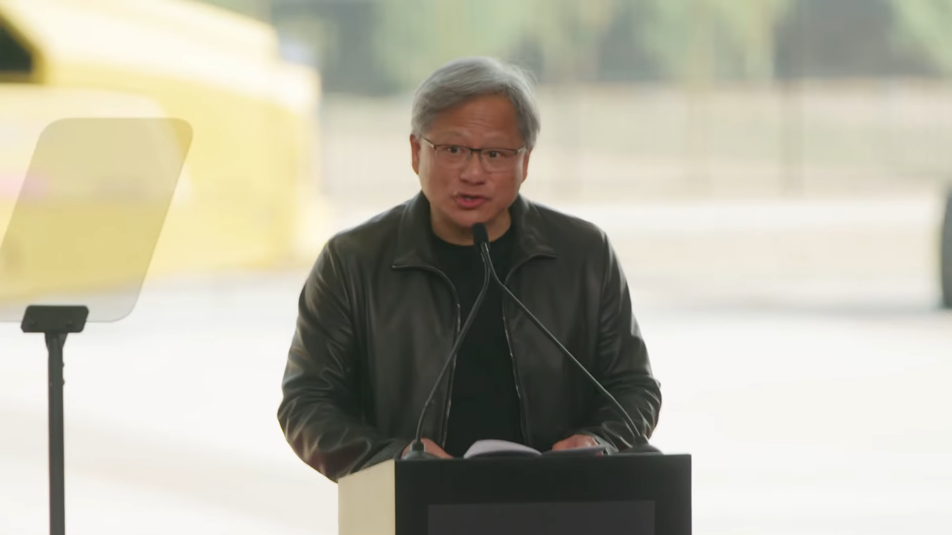 Unbranded person speaking at a podium outdoors.