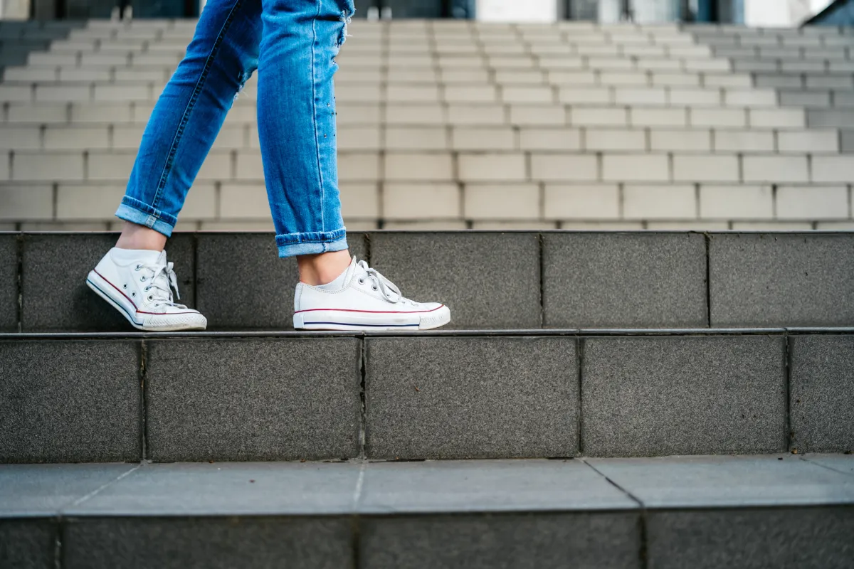 Young woman with backpack going down a staircase.