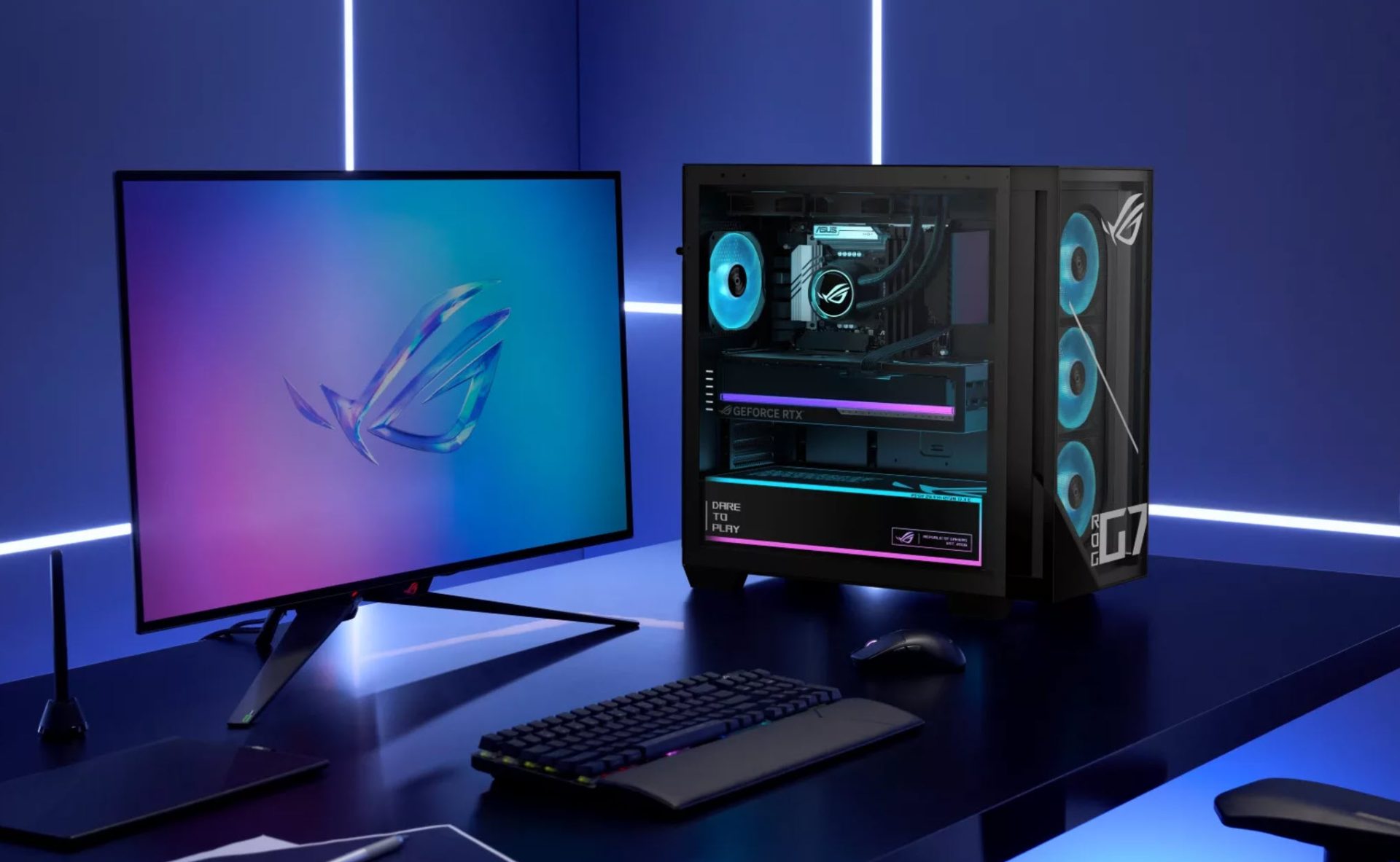An ASUS ROG desktop setup featuring a GeForce RTX graphics card and an ROG-branded monitor, with visible 'Dare to Play' text on the case.