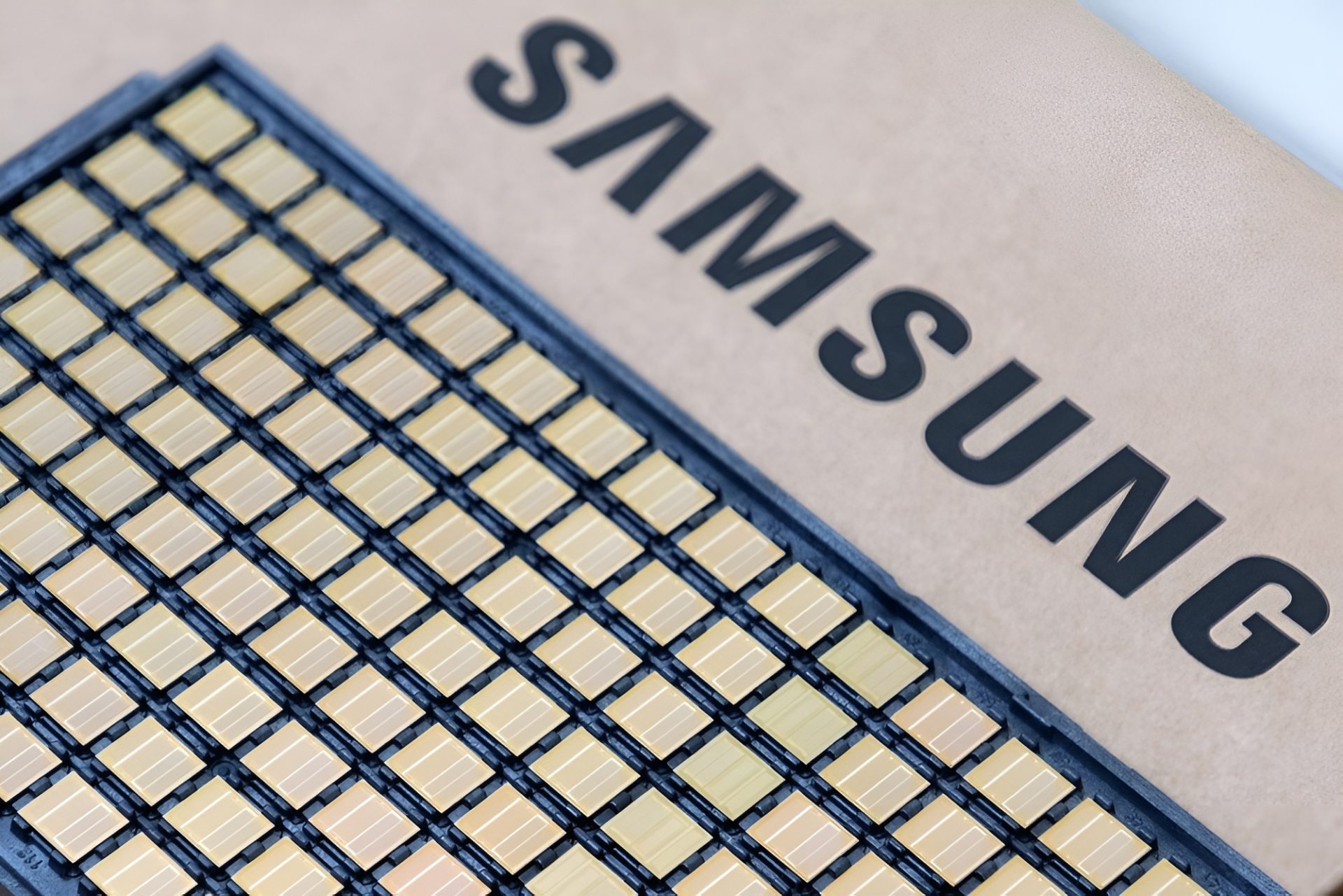 A close-up of a Samsung semiconductor chip featuring a grid of golden connectors.