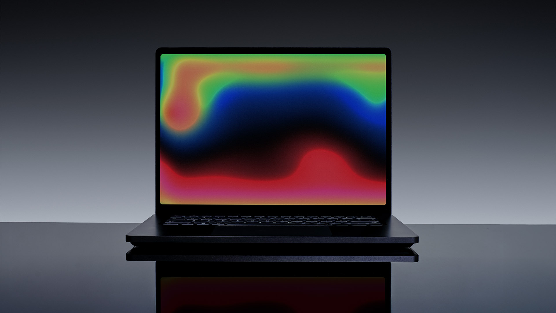 A black laptop with a colorful abstract pattern on its screen set against a gradient background.