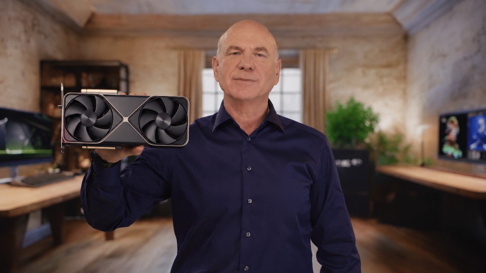 A person holds up an NVIDIA graphics card with a prominent dual-fan design in an office setting.
