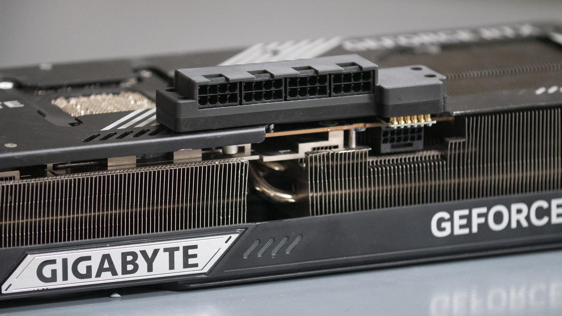 A Gigabyte graphics card with visible 'GIGABYTE' and 'GEFORCE' branding has an exposed power connector and cooling fins.